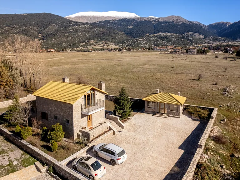 Aerial view of Anemos Mountain Villa and its paved grounds surrounded by the Parnassos mountain landscape.