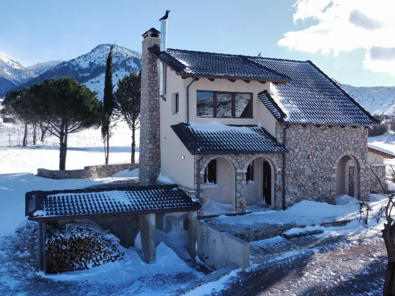 Front exterior of Villa Dianne with its stone facade, driveway and mountain setting.