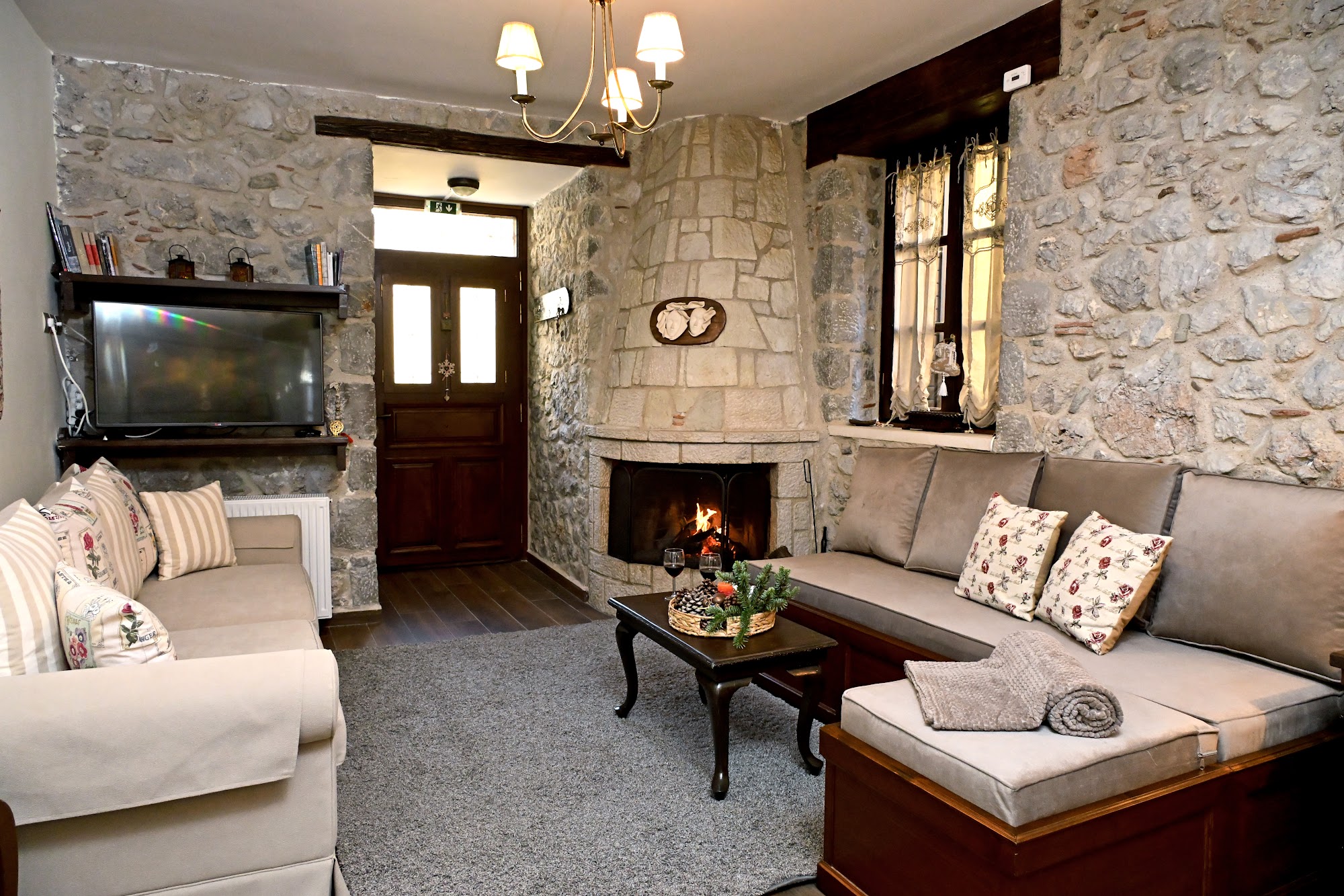 Living room with a lit stone fireplace and sofas.
