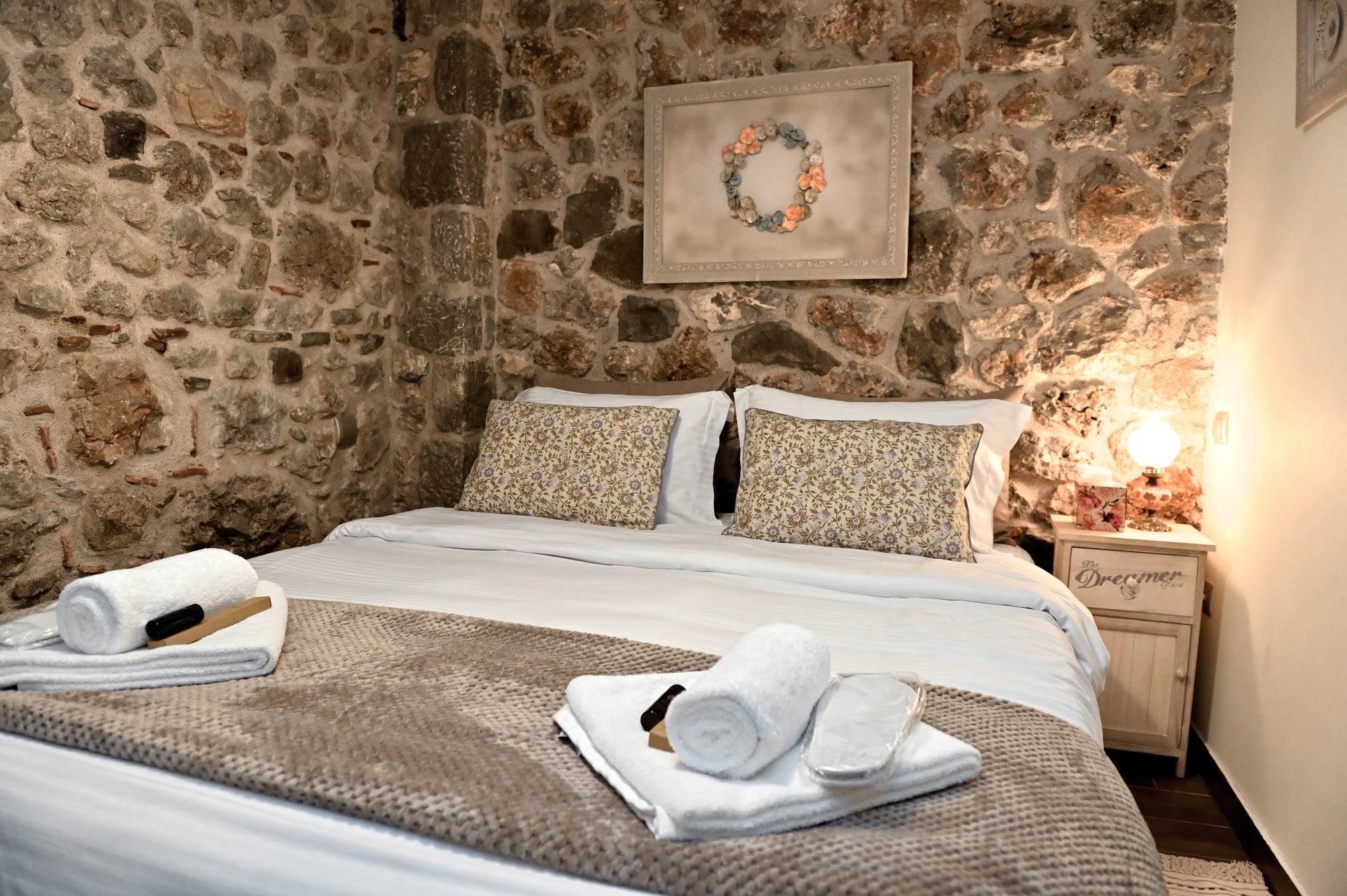 Bedroom with a textured stone wall and made bed.